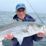 Photo of Hal Landy holding a large fish with the sea behind him