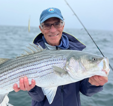 Photo of Hal Landy holding a large fish with the sea behind him